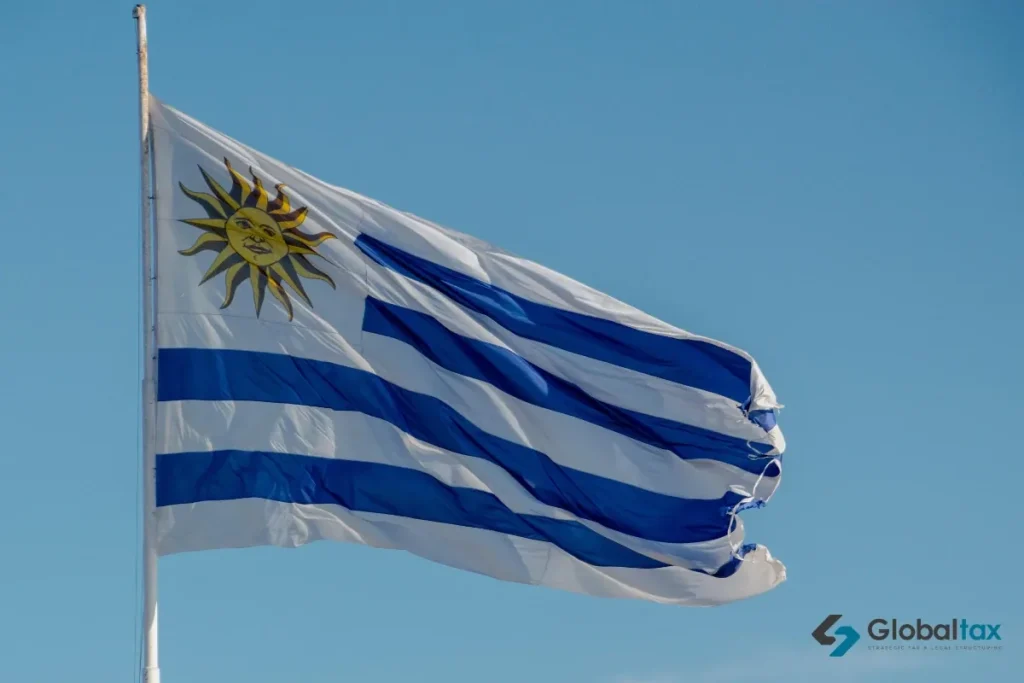 Bandeira do Uruguai com o Sol de Maio tremulando sob o céu azul