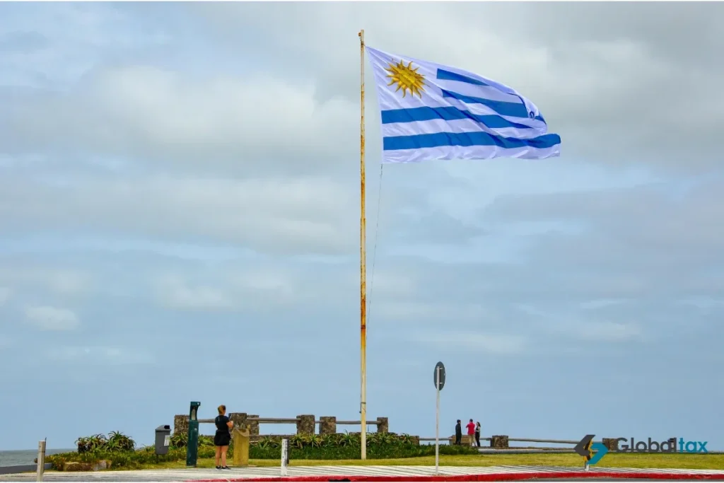 Bandeira uruguaia em um passeio à beira-mar com pessoas caminhando