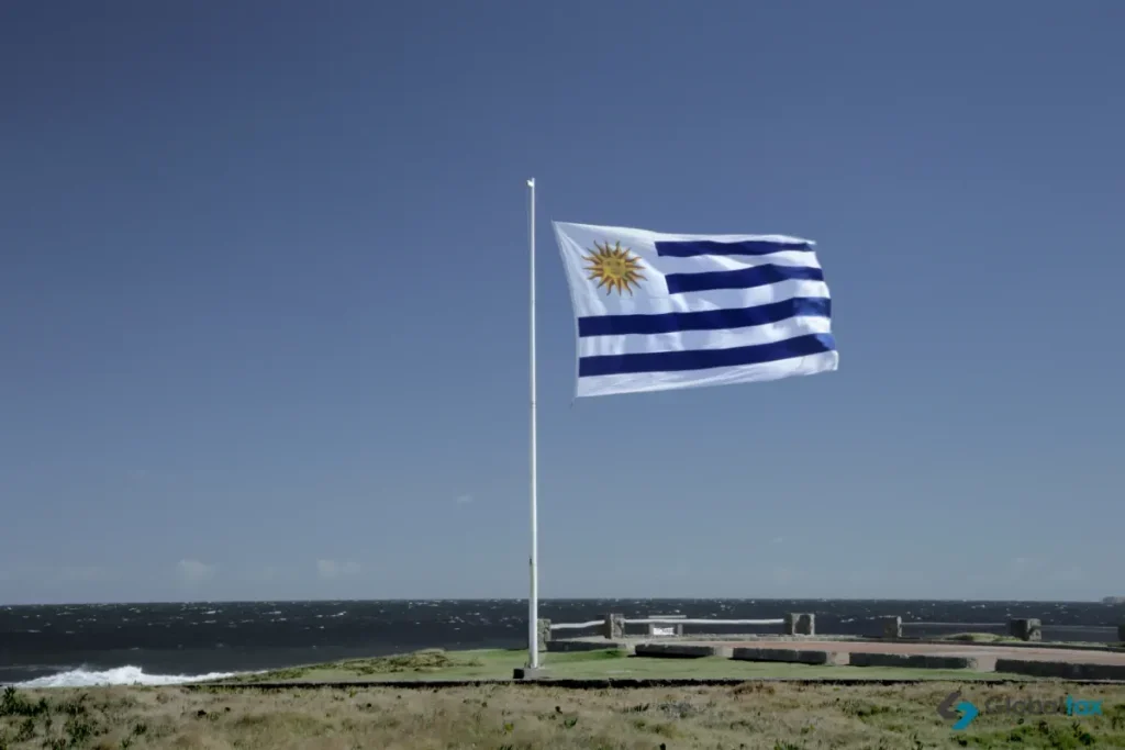 Bandeira uruguaia em um mastro diante do Rio da Prata, que separa o Uruguai da Argentina