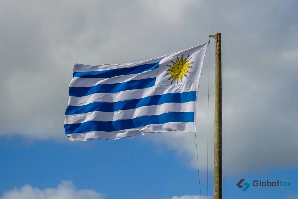 Bandeira uruguaia com o Sol de Maio em primeiro plano contra o céu